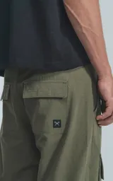 Pantalón cargo de color verde militar, corte recto y holgado, con bolsillos cargo a la altura de los muslos y detalles de costuras reforzadas en las rodillas.