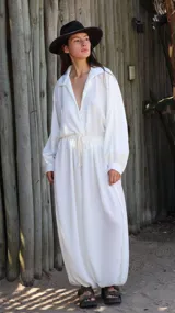Camisa de crepé color blanco, con cuello solapa, escote en V profundo y mangas largas abullonadas con puños ajustados. Presenta un diseño holgado con cintura elástica y cordón ajustable.