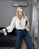 Blusa de tela cey color bordó, con escote en V y mangas largas abullonadas que terminan en puños con detalle de encaje y volados.