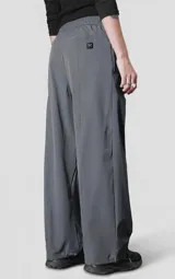 Pantalón de corte oversize confeccionado en microfibra técnica elastizada, color gris carbón. Presenta cintura elástica, bolsillos laterales, un bolsillo cargo con cierre de broche snap y sistema de elásticos con tancas en los tobillos para regular la apertura.