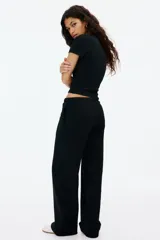 Pantalón tipo jogger de felpa color negro, con cintura elástica ajustable mediante cordón. Presenta un corte amplio y recto en las piernas, con bolsillos laterales discretos.