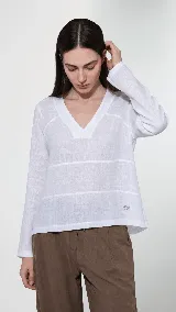Remera de lino color blanco con escote en V, manga larga y diseño con cortes horizontales en el frente. Presenta un pequeño bordado del logo en la parte inferior.