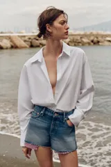 Shorts de jean tiro medio, corte mom fit, con bajo deshilachado y forro de bolsillos delanteros estampado a cuadros que asoma por debajo.