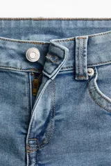Jean de denim elástico color celeste claro, de tiro bajo y corte acampanado desde la rodilla. Cuenta con bolsillos abiertos delanteros, bolsillos traseros con solapa y botón, y cierre frontal con cremallera y botón metálico.