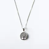 Conjunto de collar y aros a juego, elaborados en plata con dije circular que presenta un diseño de árbol de la vida sobre una base de nácar.