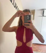 Minivestido dorado de tejido de punto con lurex, cuello halter con abertura central, cut-outs laterales y espalda descubierta.