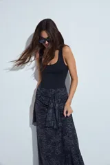 Falda larga de corte fluido con estampado de cuadros en tonos oscuros, rojizos y blancos. Presenta un diseño ligero con terminaciones onduladas en el ruedo.