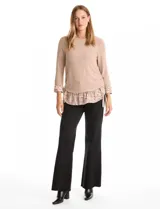 Buzo de tejido fino color beige con diseño de doble capa que simula una camisa debajo. Presenta cuello redondo, mangas largas con puños de gasa estampada en animal print, y ruedo con volado de la misma tela. Incluye detalles de frunces en los laterales.