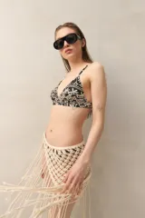 Top de bikini con estampado botánico en tonos negro y beige, de corte triangular fijo con tirantes finos.