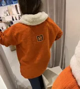 Buzo color crudo con cuello de piel sintética color crema, abertura parcial con cierre de cuero marrón y hebilla dorada, puños con ajuste de cuero marrón y bolsillos laterales.