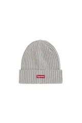 Gorro tipo beanie de tejido acanalado en color gris, con el logo de Supreme bordado en un parche rectangular rojo en la parte frontal.
