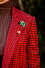 Prendedor metálico con forma de mariquita, con detalles en esmalte rojo y negro.