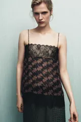 Top estampado con tejido principal de viscosa, escote recto y tirantes finos. Presenta un estampado floral en tonos marrones y negros, con detalles de encaje negro en el escote y el bajo.