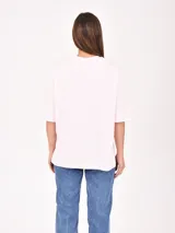 Remera de algodón color rosa pastel, con corte holgado y cuello redondo. Presenta un estampado frontal con el texto 'LOS ANGELES' en color azul y 'MALIBU CA' en color naranja.