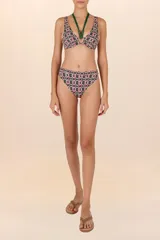 Top de bikini verde oscuro con estampado geométrico en rosa y blanco. Diseño halter con tiras al cuello y aro circular central.