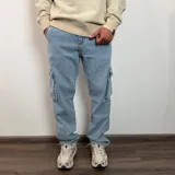 Pantalón tipo jean cargo de corte recto y tiro medio, en color azul claro lavado. Presenta bolsillos laterales con solapa y cierre de botón y cremallera.