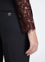 Blusa de encaje color marrón oscuro con hilos metálicos, corte entallado, cuello alto, manga larga, cierre de cremallera trasera y terminaciones efecto deshilachado.