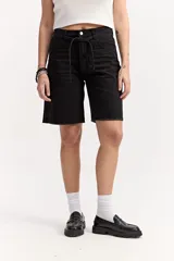 Bermuda larga de jean negro, de corte recto y tiro alto, con largo por encima de la rodilla. Cuenta con un lazo ajustable en la cintura y detalles desflecados en el ruedo.