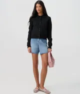 Saco de tricot negro de corte regular, con cuello polo, mangas largas y cierre frontal con botones. Presenta un diseño clásico y versátil.