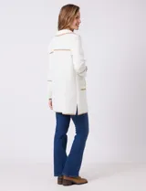 Chaqueta de silueta estructurada y calce recto, confeccionada en tejido jacquard con relieve floral. Presenta cuello con solapas, frente abierto y dos bolsillos de parche frontales. Se destaca por sus vivos a contratono que bordean las solapas, los bolsillos y las costuras horizontales, además de contar con tajos laterales en el ruedo.