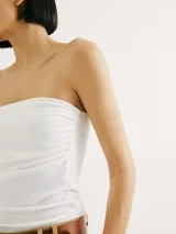 Top strapless de ajuste al cuerpo, confeccionado en tejido elástico de color blanco.