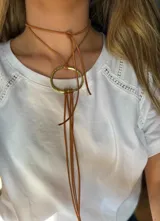 Gargantilla marrón de cuero sintético con dije circular dorado.