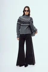 Sweater de punto color marrón, con cuello alto y diseño tejido con patrones geométricos en tonos negros y blancos en la parte superior y mangas.