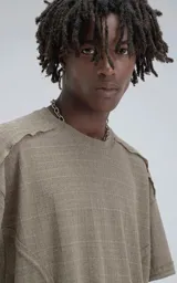 Remera de manga corta y cuello redondo, color verde militar, confeccionada en algodón premium con textura de tejido a rombos. Presenta un calce regular con recortes deshilachados en los hombros.