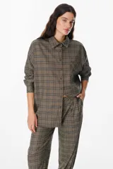 Camisa de corte oversize con estampado de cuadros, cuello clásico, cierre frontal con botones y bolsillo en el pecho.