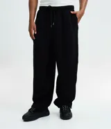 Pantalón baggy masculino de corte holgado, color beige, confeccionado en algodón con felpa. Posee cintura elástica con cordón ajustable, bolsillos delanteros y bajo con regulador por elástico.