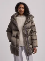 Campera puffer larga color oliva con capucha, cierre frontal con botones a presión y bolsillos laterales con cierre. Diseño acolchado con relleno de plumas.