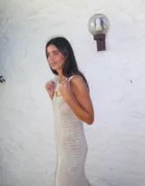 Vestido largo de crochet en color azul marino, con diseño sin mangas y cuello redondo. Presenta un detalle de apliques metálicos en la zona del pecho y un ruedo con volado de textura contrastante.