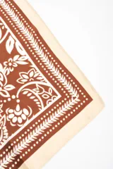 Bandana de diseño cuadrado en tono marrón y blanco con estampado de arabescos y flores, con bordes en color marfil.