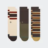 Pack de tres pares de medias Stance de caña media. Incluye un par color crema con franjas horizontales marrones y rojas, un par bicolor en marrón y verde oliva, y un par marrón con rayas horizontales multicolores. Todas cuentan con el logo de la marca bordado.