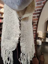 Ruana de lana color crudo, tejida a mano con diseño calado y flecos largos en el ruedo.