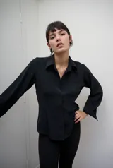 Camisa de manga larga con calce entallado y cartera frontal oculta. Presenta un diseño de superficie lisa con caída suave que se ajusta a la silueta.
