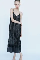 Vestido midi negro confeccionado en mezcla de viscosa con tejido satinado y efecto arrugado. Presenta escote en pico, tirantes finos ajustables, bajo con aplicación a tono y acabados deshilachados.