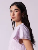 Vestido corto de lino a rayas verticales rosas y blancas, con cuello fruncido, escote en V con lazo de ajuste y mangas cortas con puntilla de crochet.