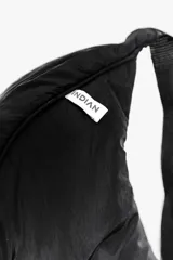 Bandolera color gris claro con forma de media luna, cierre de cremallera y correa ajustable. Incluye etiqueta metálica con el logo de la marca.