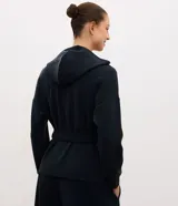 Campera utilitaria deportiva marrón de poliamida, con capucha, cierre frontal de botones, bolsillos con solapa en el pecho y lazo ajustable en la cintura.