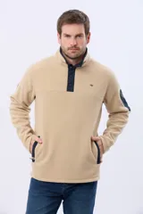 Buzo de abrigo confeccionado en tejido polar térmico, diseñado para mantener el calor y ofrecer resistencia al viento. Presenta un cuello alto con cierre frontal de broches, bolsillos laterales con cierre y un bolsillo adicional con cierre en la manga izquierda.