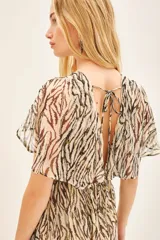 Vestido largo de viscosa jacquard con estampado de cebra en tonos marrón y negro, con detalles en lurex dorado. Presenta escote en V cruzado, elástico en la cintura y mangas cortas con volados.