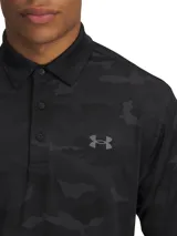 Polo de golf Under Armour modelo Playoff 3.0, con diseño de camuflaje en tonos negros y grises. Presenta cuello clásico, tapeta de tres botones y logo de la marca en el pecho. Confeccionado en tejido técnico transpirable y elástico con protección solar.