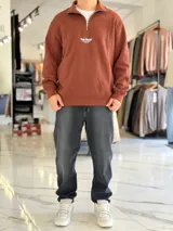 Buzo de felpa color beige con cuello alto, cierre frontal parcial, mangas largas y puños elastizados. Presenta un pequeño estampado en el pecho con la leyenda 'Top Style' y texto secundario.
