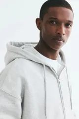 Campera con capucha y cierre frontal de H&M, color gris melange, con hombros caídos, bolsillos tipo canguro y ajuste oversized.