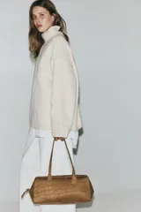 Buzo oversized de punto suave, color beige, con cuello alto acanalado y abertura posterior en V. Presenta hombros caídos, costuras decorativas verticales en el frente y terminaciones acanaladas en puños y bajo.