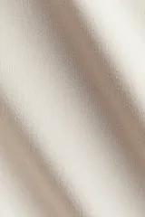 Top de manga larga confeccionado en punto suave, con diseño de hombros caídos, escote redondo y detalle de tira lateral para anudar en la cintura.