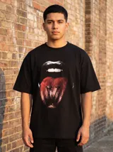 Remera negra de algodón con cuello redondo y corte oversize. Estampado frontal de una boca con labios plateados y lengua roja con la letra V.