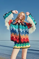 Cardigan tejido a mano con lana multicolor, con cierre frontal, cuello a la base, calce holgado y puños ajustados. Presenta flecos blancos en los puños y ruedo.