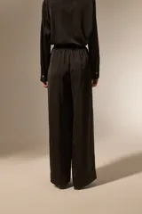 Pantalon de vestir de corte ancho y tiro alto, confeccionado en tela de viscosa con acabado satinado. Presenta cintura elástica y diseño fluido.